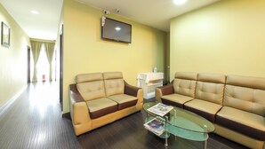 A hotel room with two leather sofas, a glass coffee table, a flat-screen TV, and a small table with an iron. - Super OYO Capital O 812 Hotel SMC Seksyen 13 (Shah Alam)
