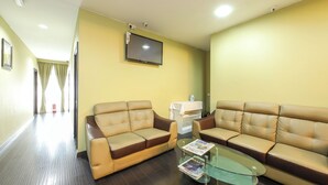 A hotel room with two leather sofas, a glass coffee table, a flat-screen TV, and a small table with an iron. - Super OYO Capital O 812 Hotel SMC Seksyen 13 (Shah Alam)