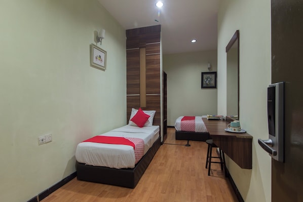 A hotel room with a bed, a desk, a mirror, and a television.