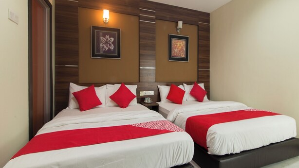 A hotel room with two beds, each with red and white bedding, wooden headboard panels, and wall-mounted light fixtures. - Super OYO Capital O 812 Hotel SMC Seksyen 13 (Shah Alam)