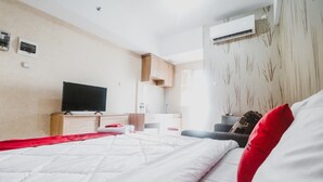 A modern hotel room with a large bed, a flat-screen TV, a desk, and an air conditioning unit. - Reddoorz Apartment @ Green Lake View Ciputat (Jakarta)