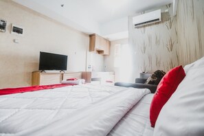 A modern hotel room with a large bed, a flat-screen TV, a desk, and an air conditioning unit. - Reddoorz Apartment @ Green Lake View Ciputat (Jakarta)