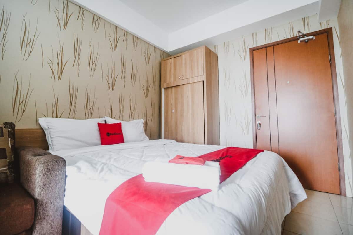 Una habitación de hotel con una cama, un armario de madera y una puerta.