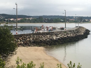 A pier with boats and construction equipment, a sandy beach, and a rocky shoreline. - Alda Barraña Playa (Boiro)