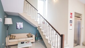 Un interior moderno con una escalera, un sofá, una mesa de centro y una lámpara.