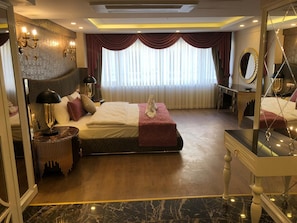 Ein modernes Schlafzimmer mit einem großen Bett, Nachttischen, einem Spiegel und Blick auf die Stadt durch große Fenster.