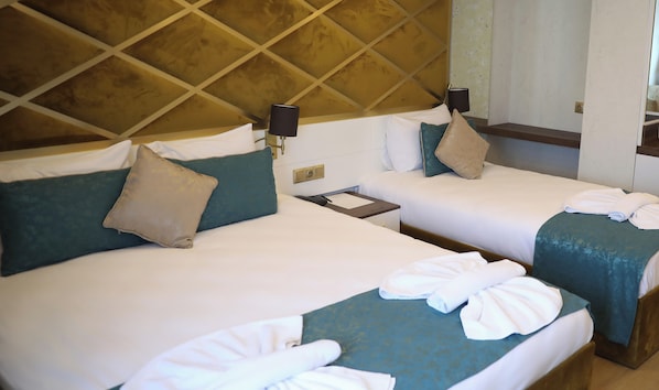 Une chambre d’hôtel avec deux lits, chacun équipé d’un oreiller, d’une table de chevet avec une lampe et d’une serviette pliée posée sur le lit.