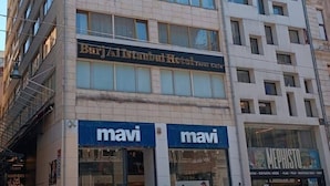Un edificio de varios pisos con un cartel que dice 'Burj Al Istanbul Hotel' y dos escaparates 'mavi'.