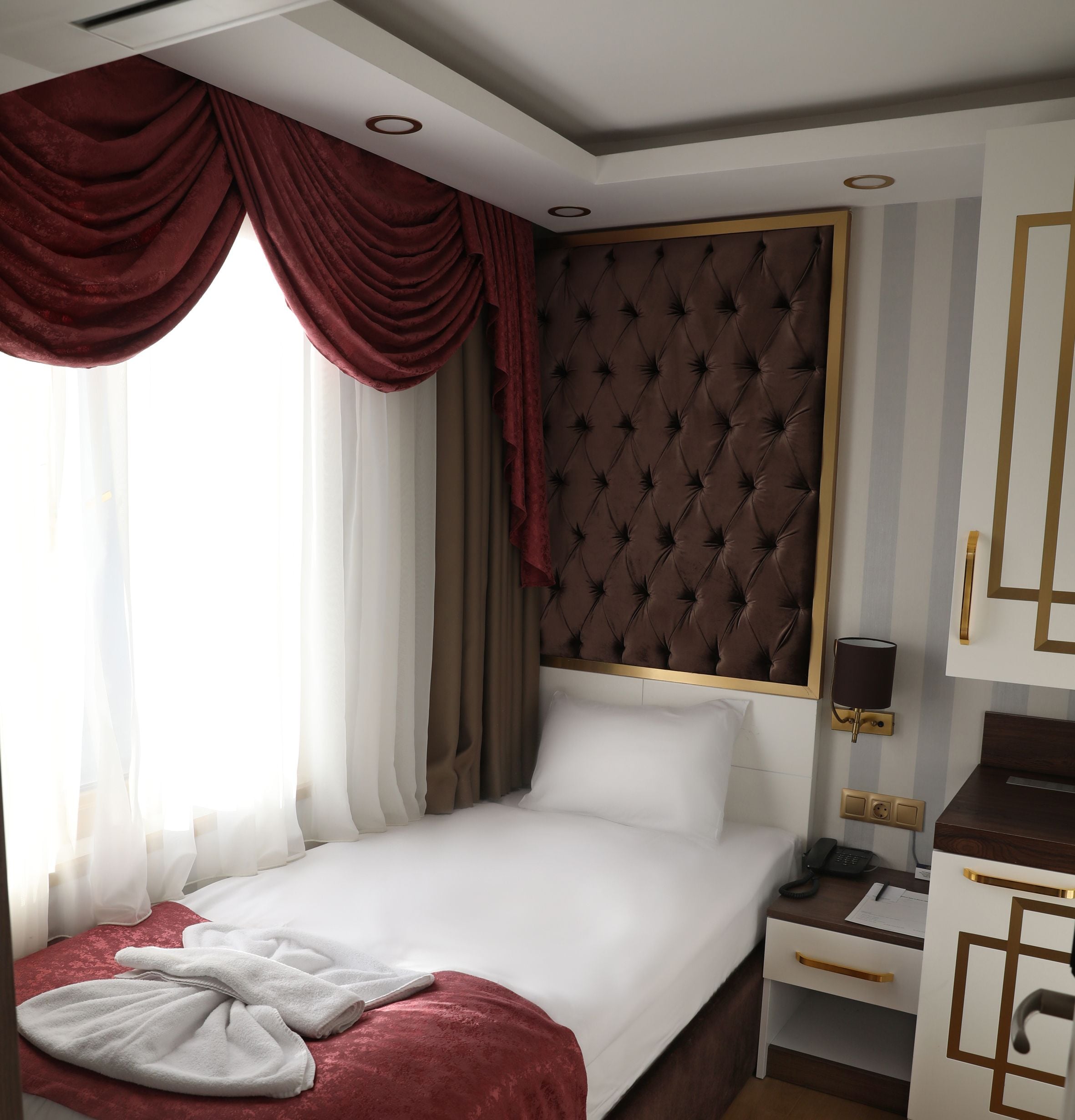 A hotel room with a bed, a bedside table, a lamp, and a telephone.