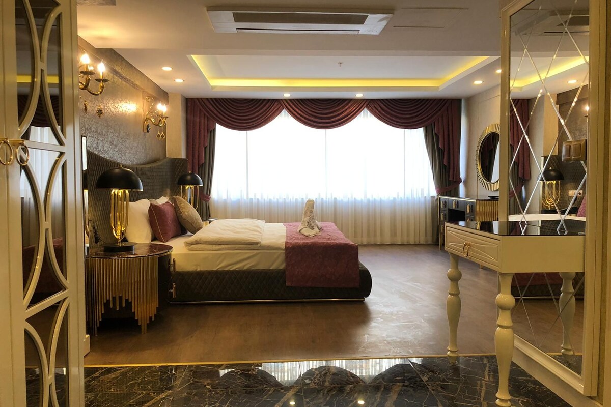 Une chambre à coucher avec un lit, une table de chevet, une lampe et un grand miroir.
