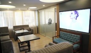 Ein Hotelzimmer mit Sitzgelegenheit, einem Fernseher und Blick auf die Stadt.