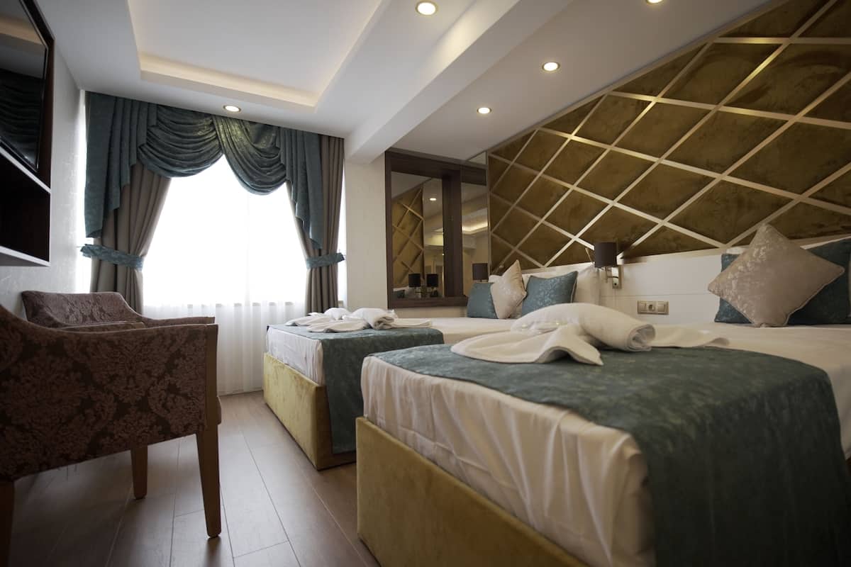 Ein Hotelzimmer mit zwei Betten, einer Sitzecke und einem großen Spiegel.