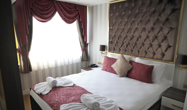 A hotel room with a large bed, a headboard, a bedside table, a lamp, and a window with curtains. - Burj Al Istanbul (Istanbul)