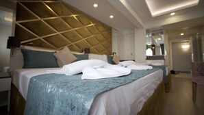 Una habitación de hotel moderna con una cama grande, un cabecero de diseño geométrico y un baño a la vista al fondo.