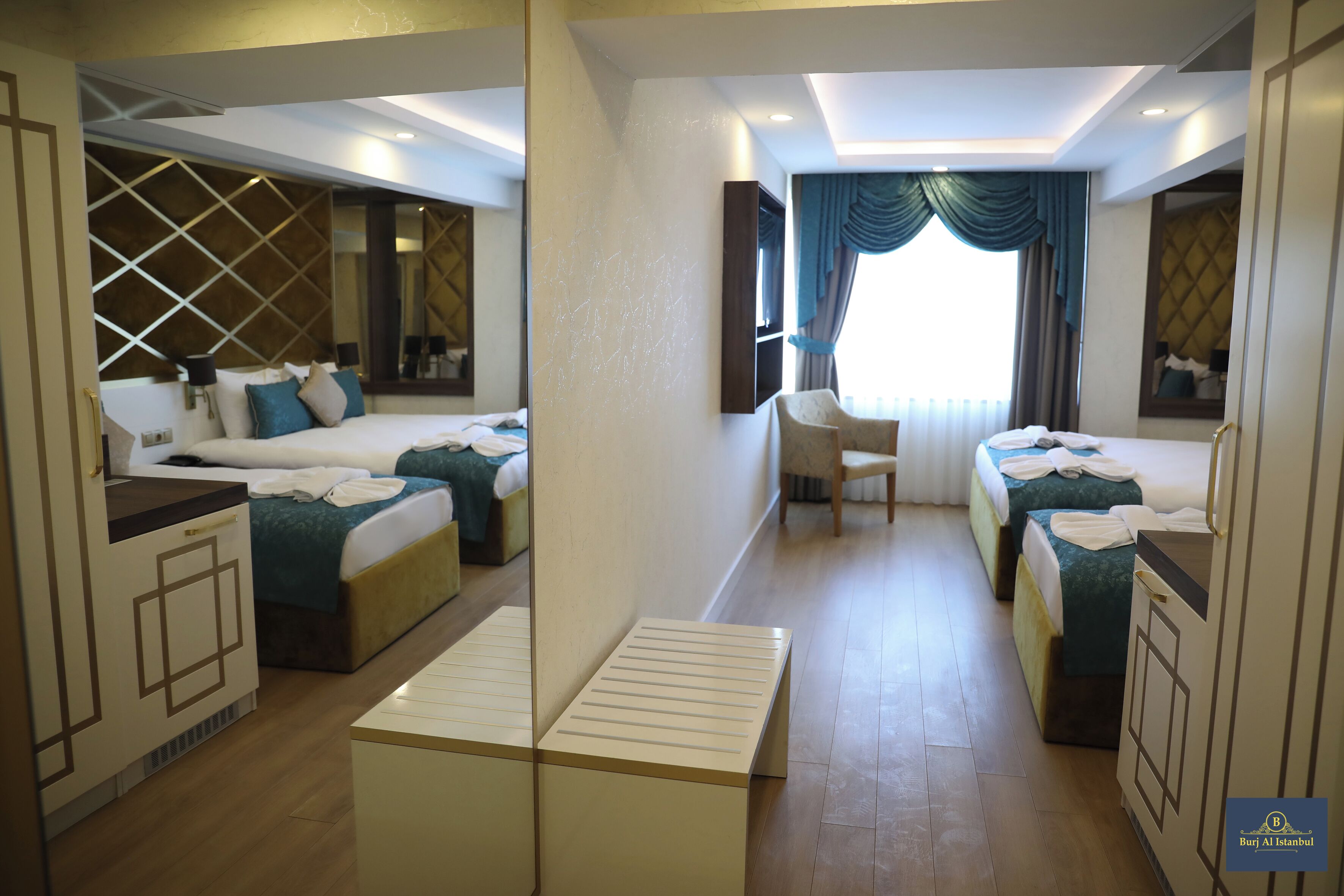 A hotel room with two beds, a desk, and a mirror.