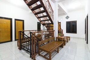 Una escalera con barandales de metal ornamentados, bancos de madera y puertas numeradas 7 y 8.