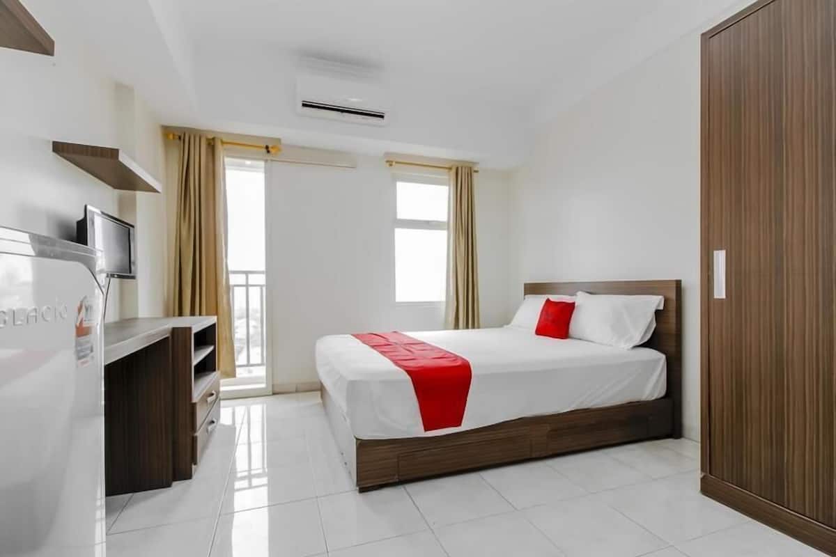 A modern hotel room with a bed, a TV, and a wardrobe.