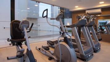 A gym with stationary bikes, treadmills, and a mirrored wall.