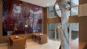 Ein modernes Interieur mit einem großen abstrakten Gemälde, einer spiralförmigen Skulptur und einem Essbereich mit zwei Tischen und Stühlen.