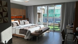 Ein modernes Hotelzimmer mit einem großen Bett, einem Schreibtisch und Blick auf einen Pool und einen Außenbereich.