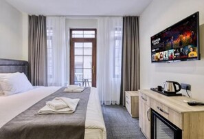 A hotel room with a bed, a TV mounted on the wall, a desk with a kettle, and a window with curtains. - Hub Inn Pera (Istanbul)