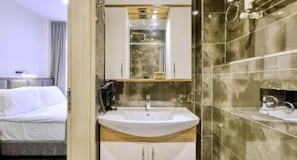 A hotel bathroom with a sink, mirror, and shower. - Hub Inn Pera (Istanbul)