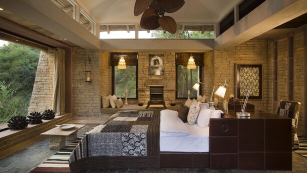 A spacious bedroom with a large bed, a fireplace, and a view of the outdoors.