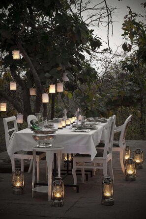A table set outdoors with white chairs, surrounded by lanterns, and a white tablecloth. - Pashan Garh A Taj Safari Panna National Park (Pawai)