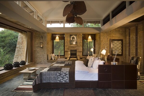 A spacious bedroom with a large bed, a fireplace, and a view of the outdoors. - Pashan Garh A Taj Safari Panna National Park (Pawai)