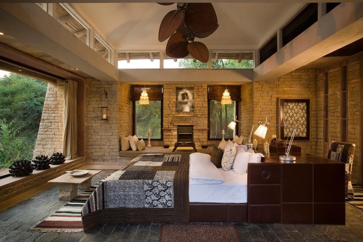 A bedroom with a large bed, a fireplace, and a view of the outdoors.