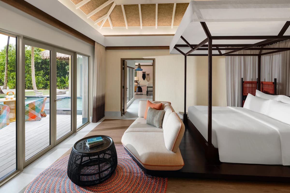 Une chambre d’hôtel moderne avec une grande fenêtre, un canapé, un lit et une petite table.