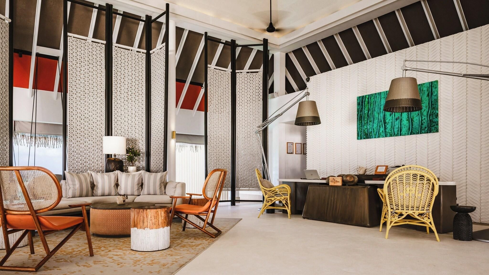 A spacious living area with a sofa, chairs, a coffee table, and a desk with a laptop.