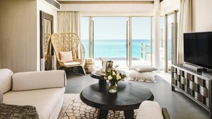 A modern living room with a sofa, a round table with a vase, a television, and a view of the ocean. - Intercontinental Maldives Maamunagau Resort (Maamunagau Island)