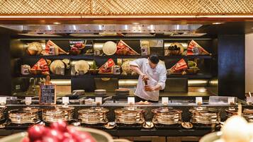 A chef preparing food in a kitchen with traditional decor and a variety of dishes displayed on shelves.