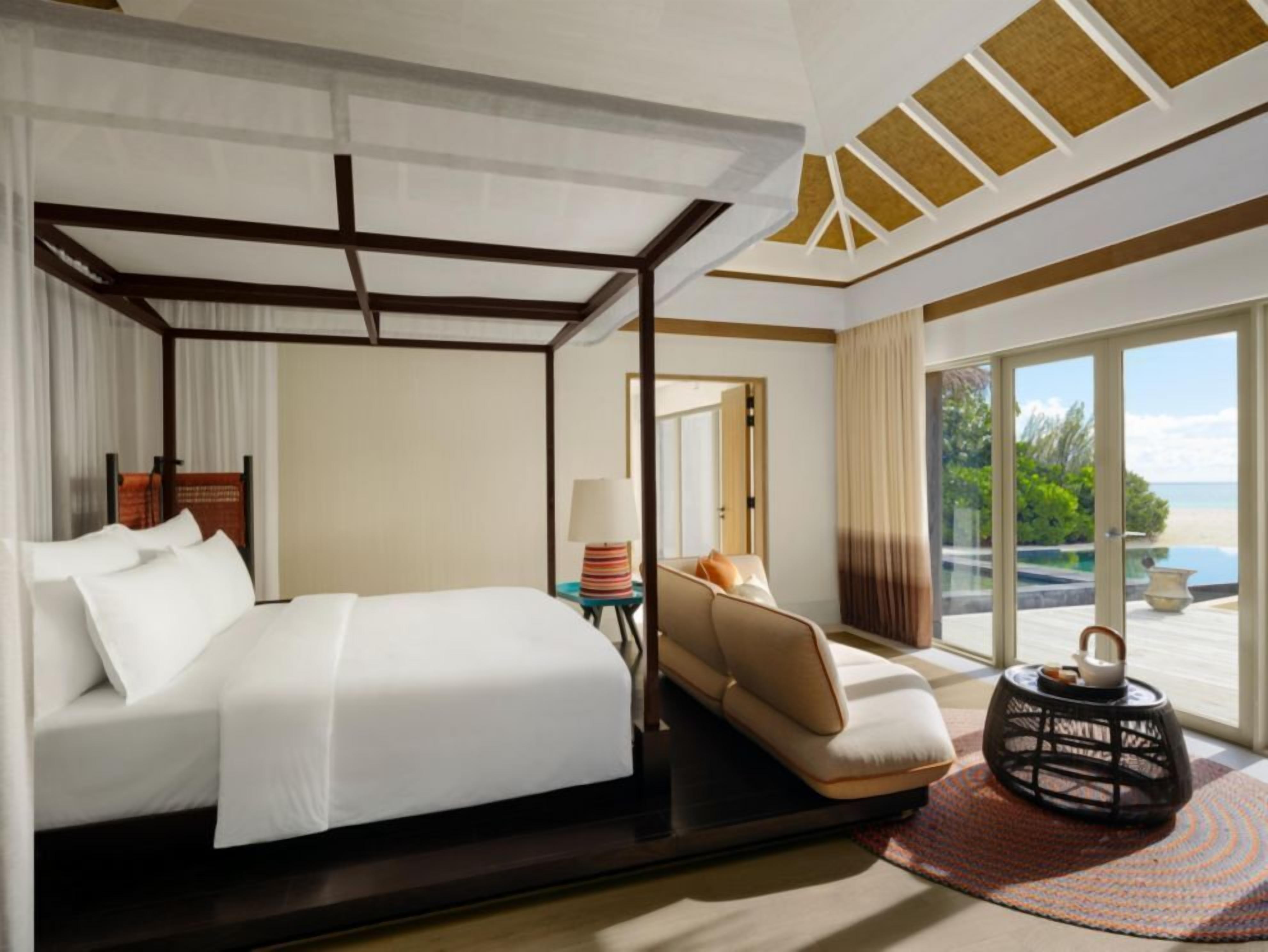 Une chambre d’hôtel comprenant un lit, un canapé, une petite table avec une lampe, un objet décoratif et une vue sur l’extérieur.