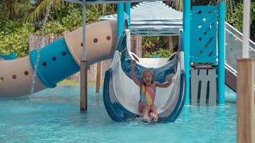 A water slide at a water park with a blue and white slide, a blue and white striped canopy, and a pool area.