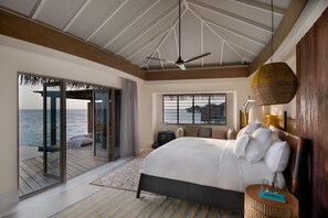 Un dormitorio con cama, ventilador de techo, vista al mar y un ventanal amplio.
