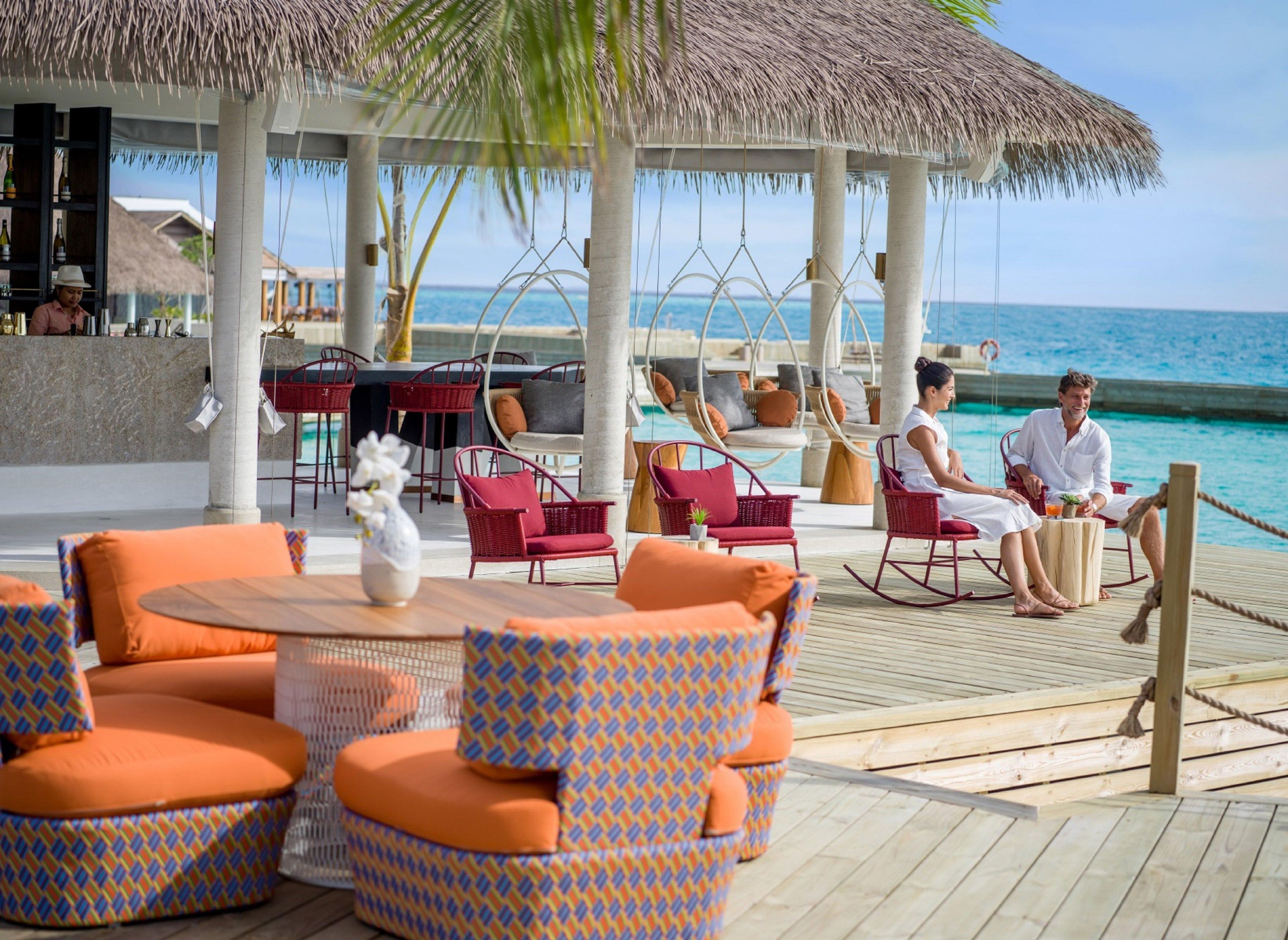 A resort deck with outdoor seating, a bar area, and a view of the ocean.