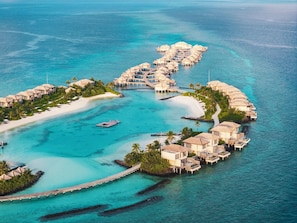 An overwater resort with multiple bungalow-style accommodations connected by walkways.