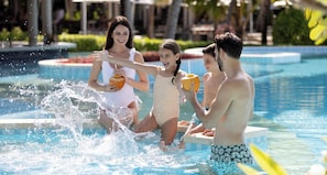 A pool area with a water feature, a lounge chair, and a dining area with tables and chairs.
