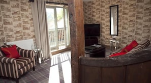 A living room with striped sofas, a television, and patterned wallpaper. - The Greenway (Cheltenham)