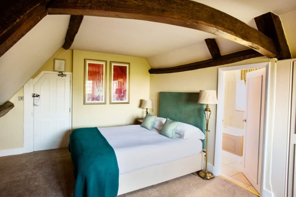 Un dormitorio con una cama, un mesita de noche, una lámpara y una puerta.