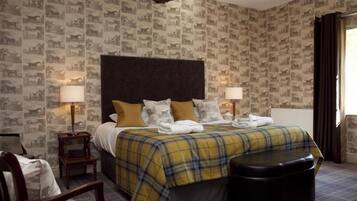 A hotel room with a large bed, two bedside lamps, a headboard, and a plaid bedspread.