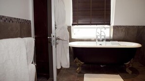 A bathroom with a freestanding bathtub, a window with blinds, and a towel rack. - The Greenway (Cheltenham)