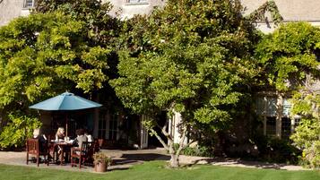 A large stone building with a garden patio area.