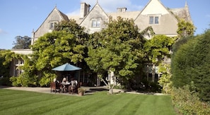 A large, historic building with a well-maintained lawn and outdoor seating area. - The Greenway (Cheltenham)