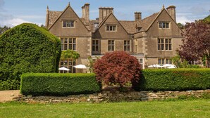 A large, multi-story building with a symmetrical facade, stone walls, and multiple chimneys. - The Greenway (Cheltenham)