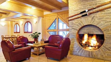 A cozy room with a stone fireplace, leather sofas, wooden beams, and a dining area with a table and chairs.