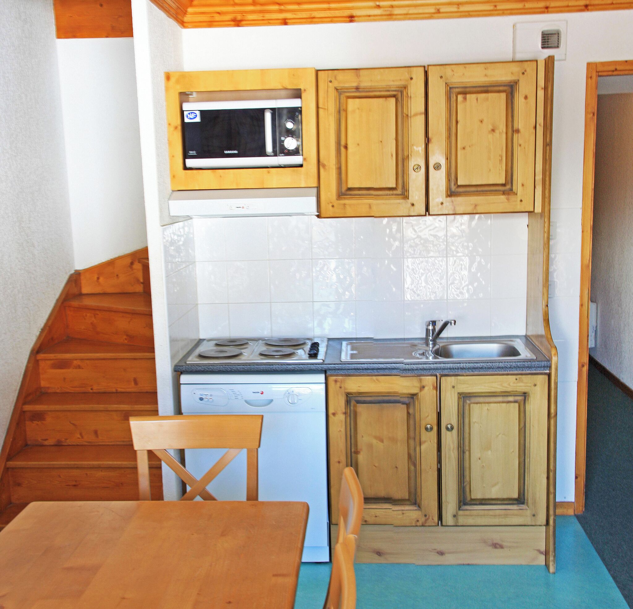 A compact kitchen with wooden cabinets, a microwave, a dishwasher, a stove, and a sink.