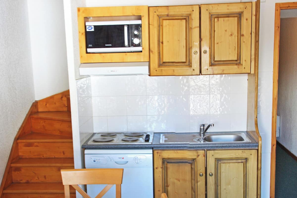 Une cuisine compacte dotée de meubles en bois, d’un four à micro-ondes, d’un lave-vaisselle, d’une cuisinière et d’un évier.